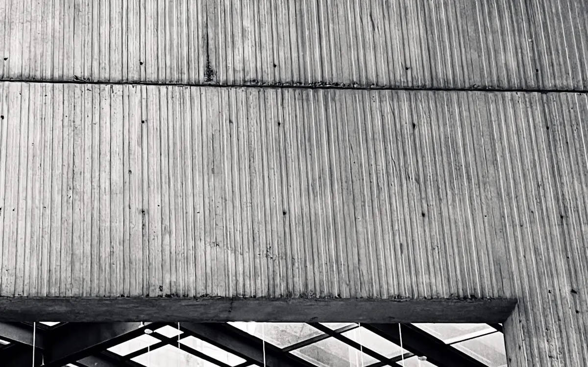 Board-formed concrete ceiling meeting a steel and glass roof